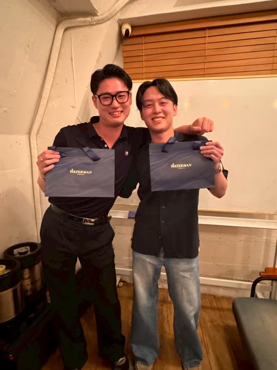 表彰の記念品を手にしたメンバー2人