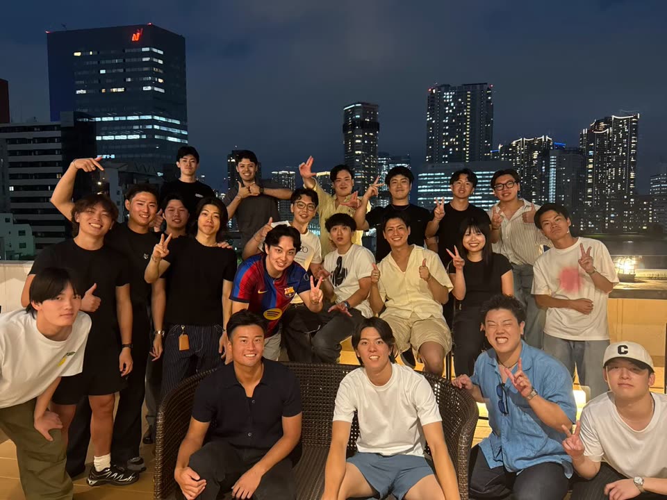 夜景を背にした屋上でのメンバーの集合写真