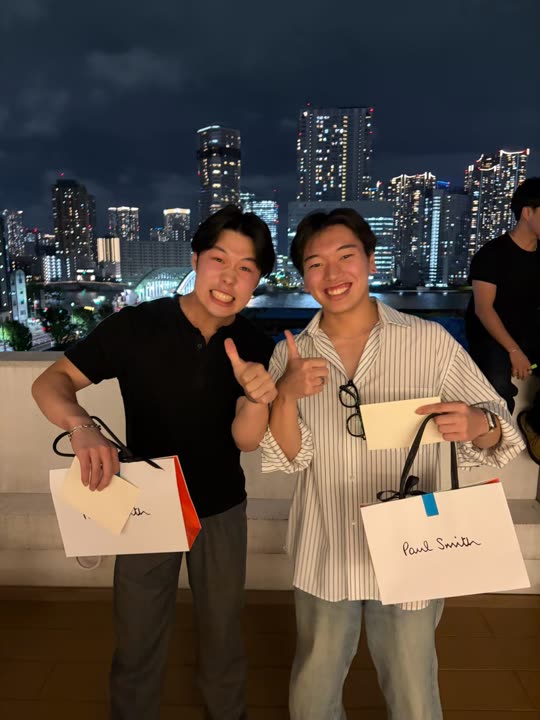 夜景の前で記念品を手にしたメンバー2人